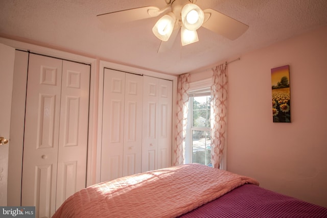 bedroom with multiple closets, a textured ceiling, and ceiling fan