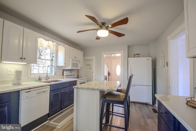 kitchen with sink, white appliances, white cabinetry, a center island, and blue cabinets