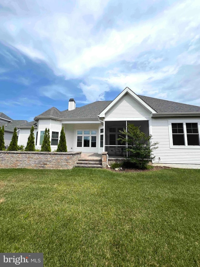 ranch-style home featuring a sunroom, a chimney, a shingled roof, and a front yard