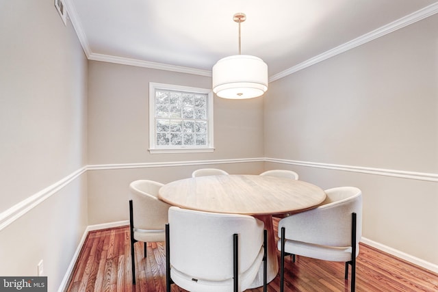 dining area featuring hardwood / wood-style flooring and crown molding