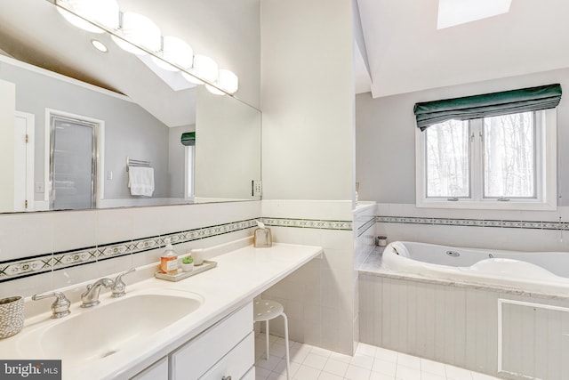 bathroom with lofted ceiling, tile walls, a tub to relax in, vanity, and tile patterned floors