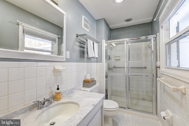 bathroom featuring toilet, an enclosed shower, tile walls, vanity, and tile patterned flooring