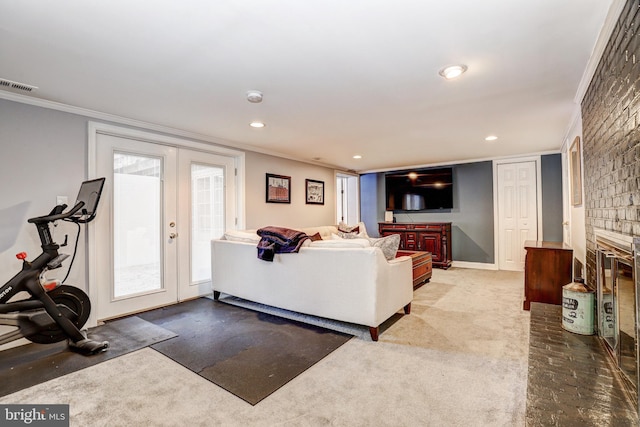 living room featuring crown molding, carpet floors, a fireplace, a healthy amount of sunlight, and french doors