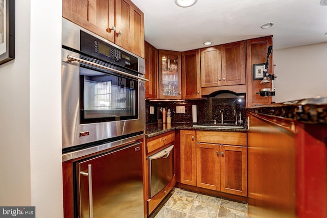 kitchen with backsplash, fridge, sink, and dark stone countertops