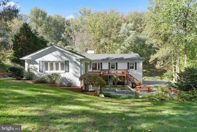 rear view of house featuring a wooden deck and a lawn