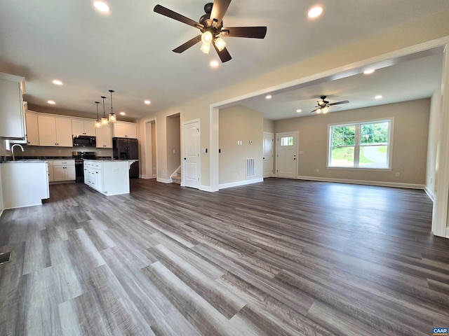 unfurnished living room with dark wood-type flooring, sink, and ceiling fan