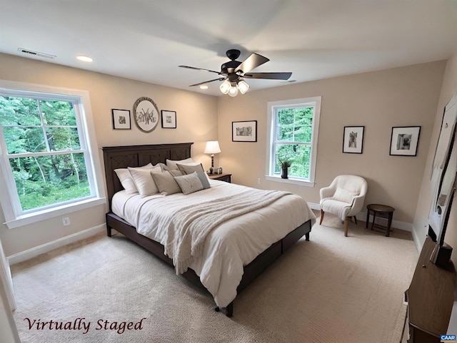 bedroom with multiple windows, light carpet, and ceiling fan