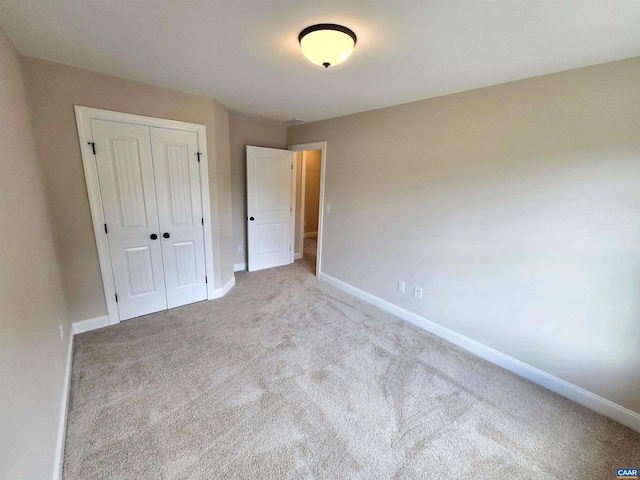 unfurnished bedroom featuring light colored carpet and a closet