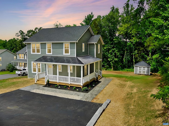 view of front facade featuring a shed, a yard, and a porch