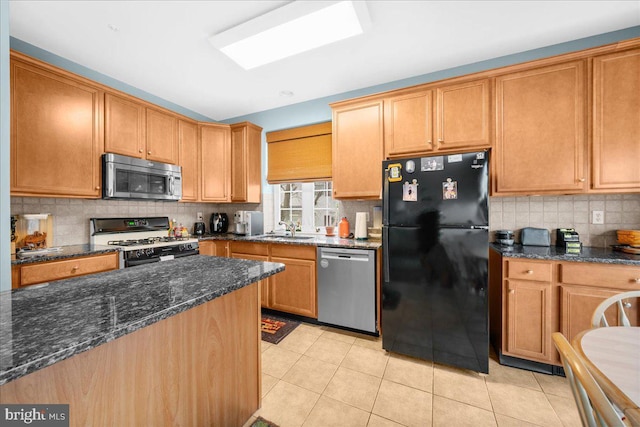 kitchen with light tile patterned flooring, sink, dark stone countertops, backsplash, and stainless steel appliances