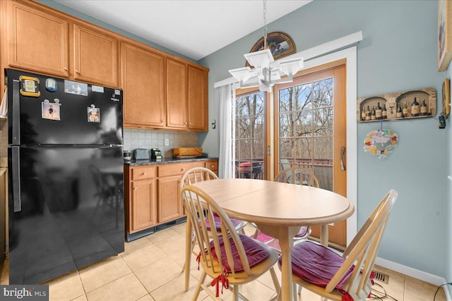 kitchen featuring pendant lighting, tasteful backsplash, a chandelier, light tile patterned floors, and black fridge