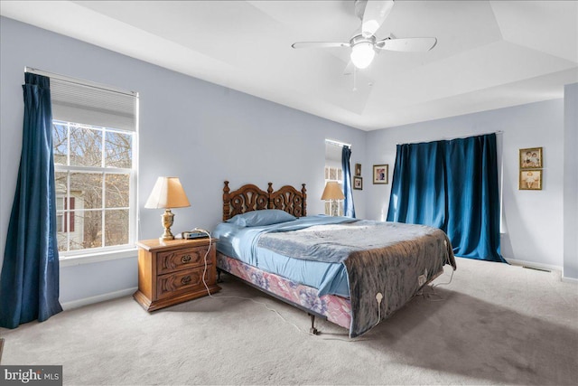 bedroom featuring ceiling fan, a raised ceiling, and carpet floors