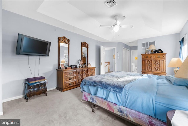 carpeted bedroom with a closet, a raised ceiling, and ceiling fan