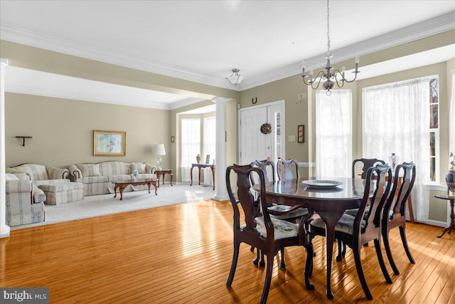 dining area with a notable chandelier, crown molding, light hardwood / wood-style floors, and ornate columns