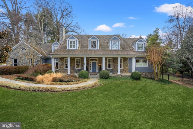 cape cod-style house featuring stone siding, a chimney, fence, a front lawn, and a porch