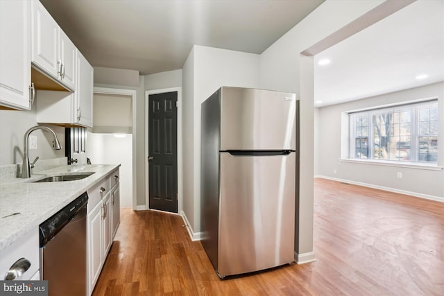 kitchen with stainless steel appliances, sink, white cabinets, and light stone counters