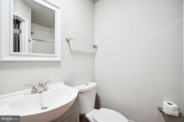 bathroom featuring vanity, walk in shower, and toilet