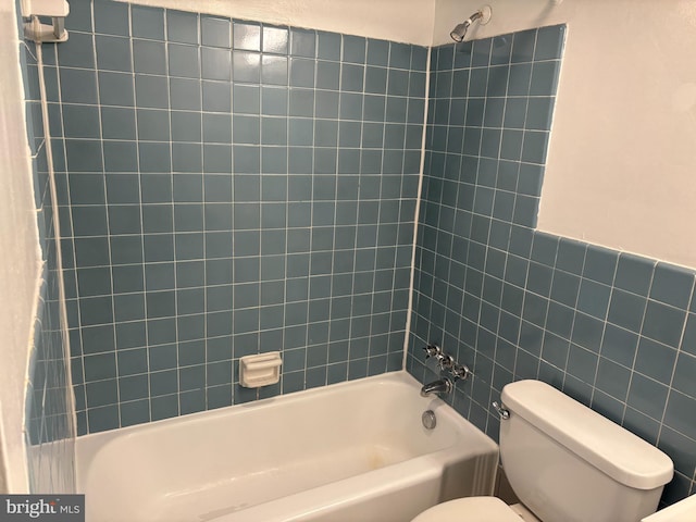 bathroom featuring tiled shower / bath combo, tile walls, and toilet