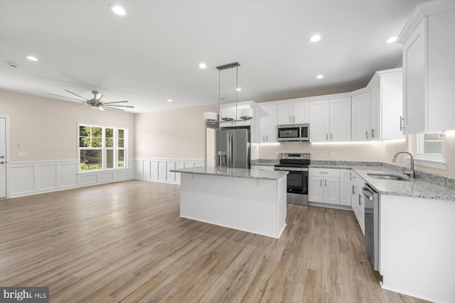 kitchen with sink, ceiling fan, appliances with stainless steel finishes, white cabinetry, and a center island