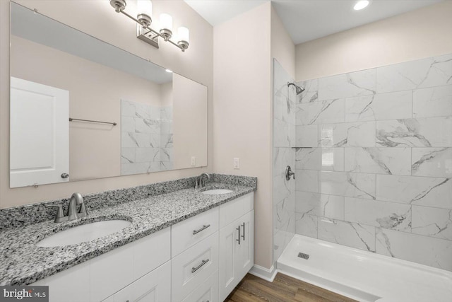 bathroom with wood-type flooring, vanity, and a tile shower