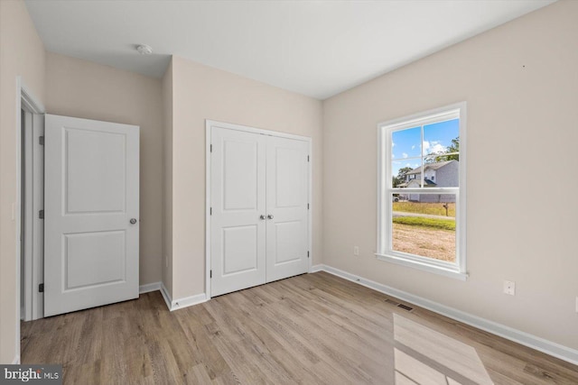 unfurnished bedroom with a closet and light wood-type flooring