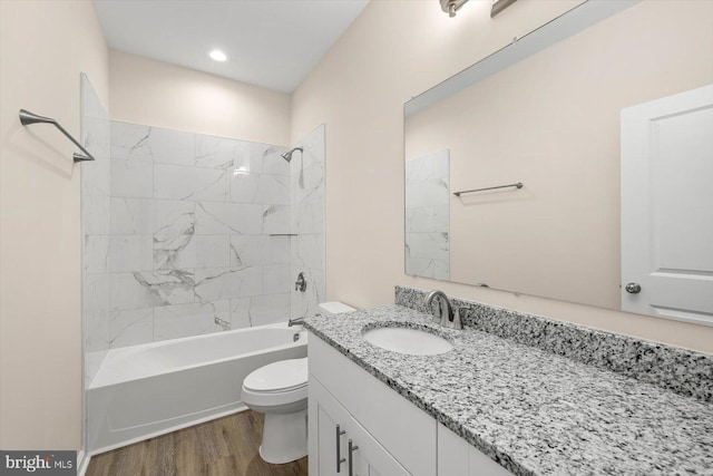 full bathroom with wood-type flooring, toilet, tiled shower / bath combo, and vanity