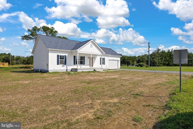 view of front of home featuring a garage, covered porch, and a front yard