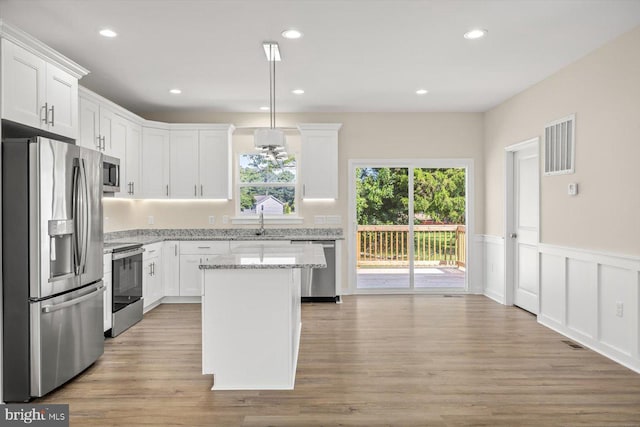 kitchen featuring white cabinetry, light stone counters, a kitchen island, pendant lighting, and stainless steel appliances