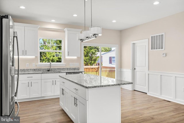 kitchen featuring white cabinetry, stainless steel fridge, a center island, and sink