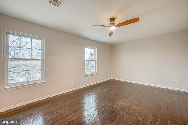 spare room featuring dark wood-style flooring, visible vents, ceiling fan, and baseboards