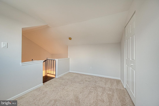 additional living space featuring light carpet, lofted ceiling, and baseboards