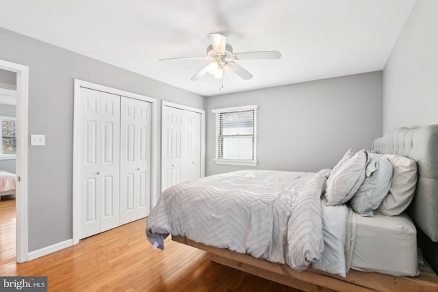 bedroom featuring two closets, ceiling fan, and hardwood / wood-style flooring