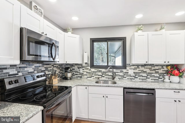 kitchen featuring stainless steel appliances, light stone countertops, sink, and white cabinets