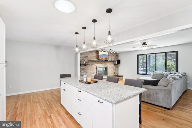 kitchen featuring white cabinetry, hanging light fixtures, light stone countertops, and light wood-type flooring