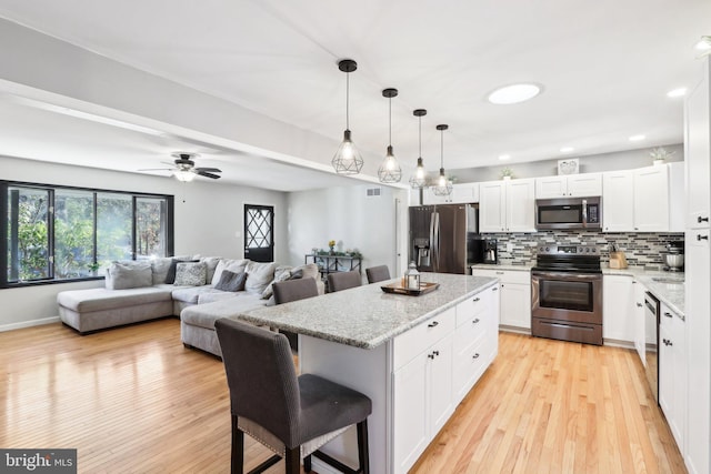 kitchen featuring white cabinetry, appliances with stainless steel finishes, a breakfast bar, and pendant lighting