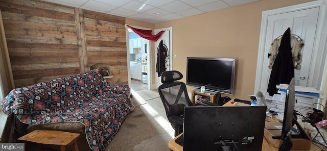 carpeted living room featuring a paneled ceiling and wood walls