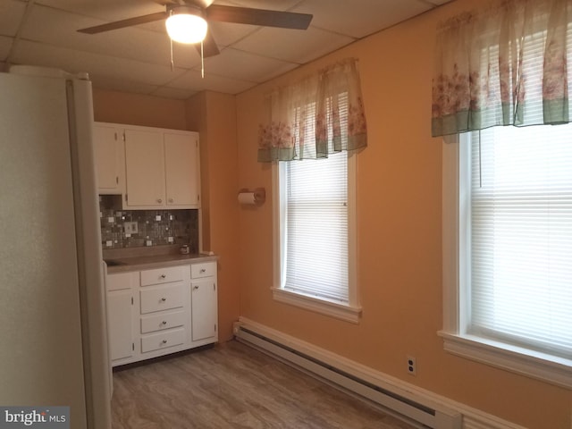 kitchen featuring white cabinetry, a baseboard radiator, and a wealth of natural light