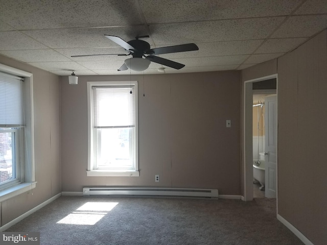 empty room with ceiling fan, a baseboard radiator, carpet, and a drop ceiling