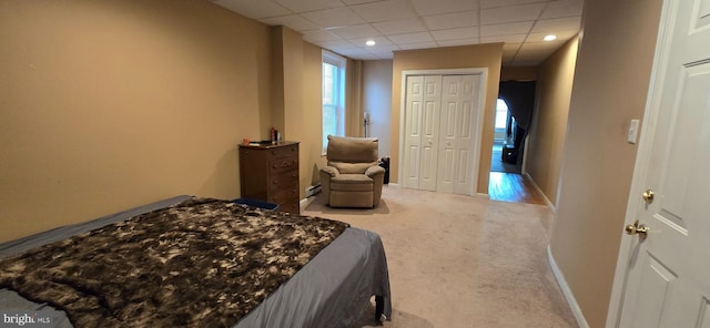 carpeted bedroom featuring a paneled ceiling and a closet