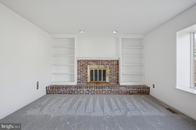 unfurnished living room with dark colored carpet, built in features, and a fireplace