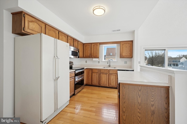 kitchen with sink, stainless steel appliances, and light wood-type flooring