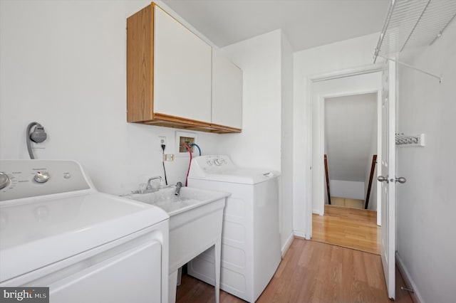 laundry area with cabinets, washing machine and dryer, and light hardwood / wood-style floors