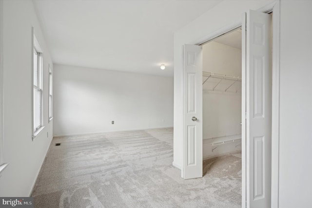 interior space featuring a spacious closet, light colored carpet, and a closet