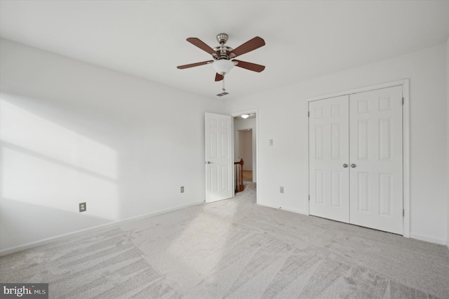 unfurnished bedroom featuring ceiling fan, a closet, and light carpet