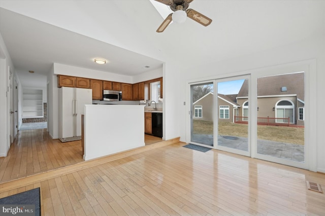 kitchen featuring black dishwasher, sink, white fridge, a center island, and light hardwood / wood-style floors