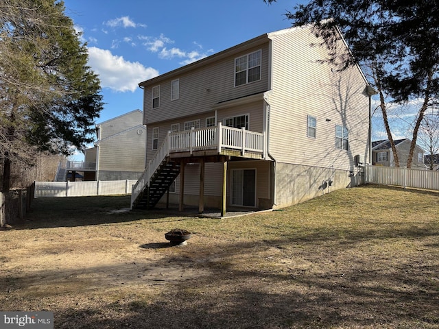 rear view of property with a deck, a fenced backyard, a fire pit, stairs, and a lawn