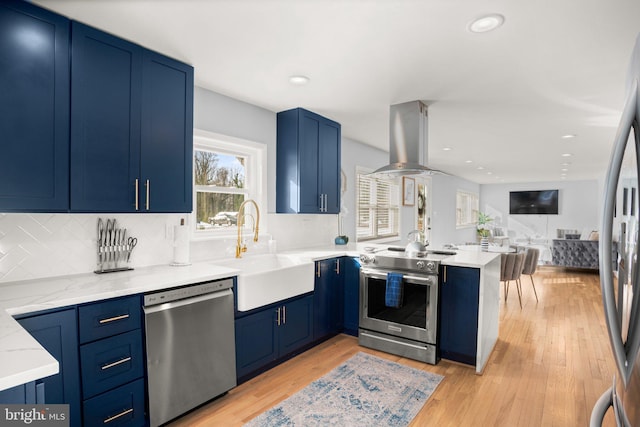 kitchen with sink, stainless steel appliances, island range hood, kitchen peninsula, and light wood-type flooring