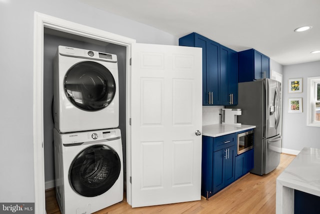 laundry area featuring stacked washer and clothes dryer and light hardwood / wood-style flooring