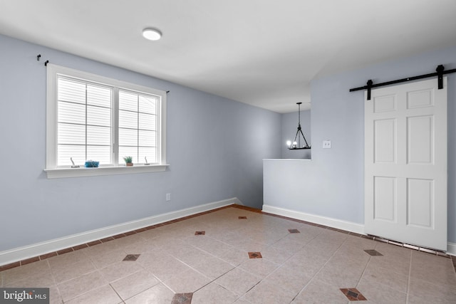 empty room with light tile patterned flooring, a barn door, and an inviting chandelier