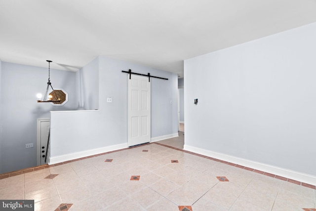 empty room featuring tile patterned floors, a barn door, and a chandelier